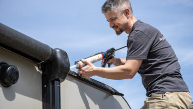 A man using caulk on the roof of an RV.