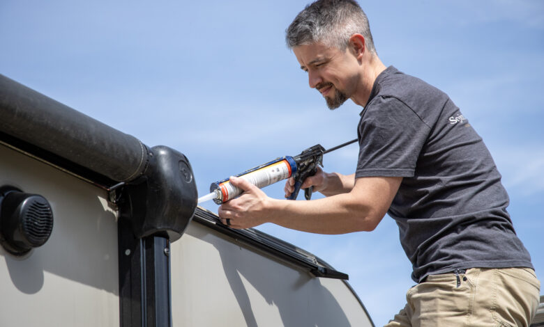 Comprehensive Summer RV Maintenance & Pre-Trip Checklist 2 A man using caulk on the roof of an RV.