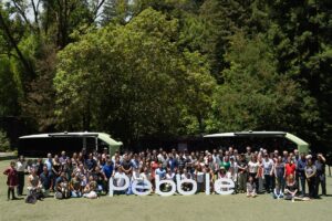 Pebble Begins Travel Trailer Deliveries & Debuts Auto Dump System 2 A gathering of people behind a Pebble logo and in front of two green Pebble Flow RVs for the delivery event.