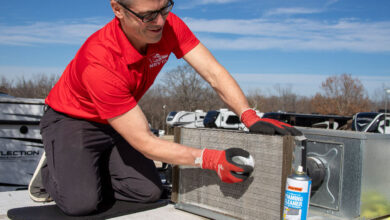 RV technician cleaning an air conditioner coil on an RV rooftop.