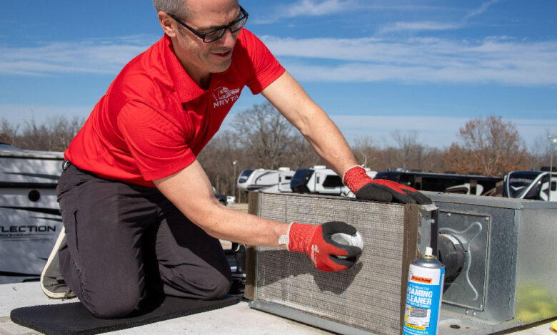 Summer RV Maintenance Guide: 7 Tips Dealers Should Share With Customers 2 RV technician cleaning an air conditioner coil on an RV rooftop.