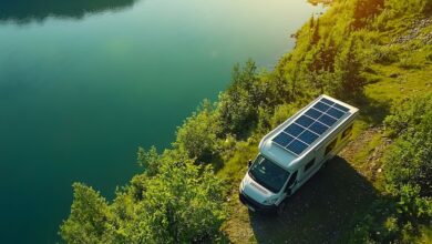 An RV pictured in nature with solar panels on its roof
