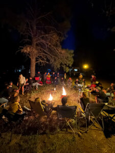 A group of fernweh campers bonding in the dark around a campfire.