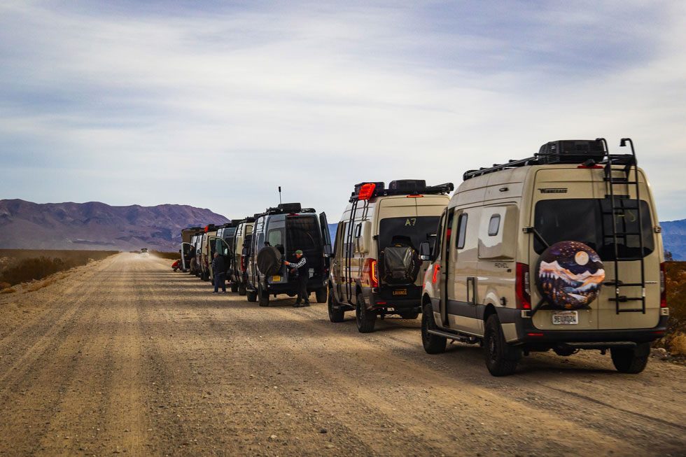 A line of camper vans and RVs on a dirt road in Death Valley, California, near Eureka Dunes. 