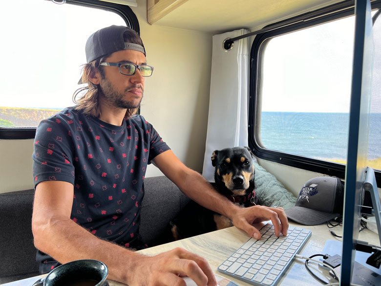 Influencer Marketing Produces Road-Tested Results 8 A man sitting in a truck camper with a dog next to him as he edits video on a computer.