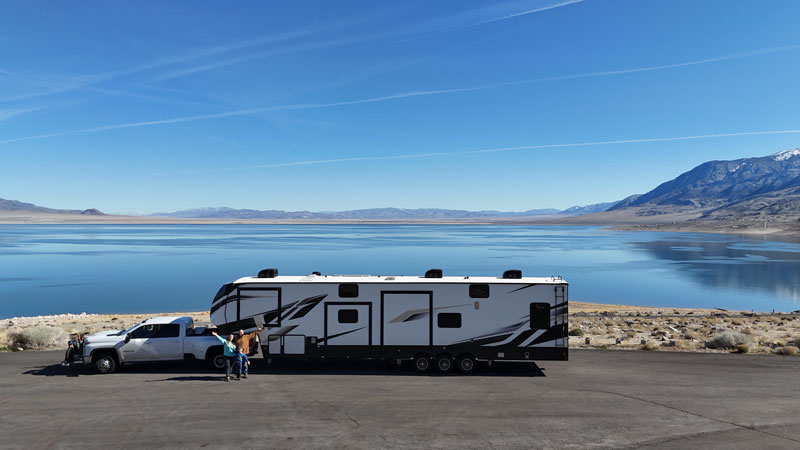 Influencer Marketing Produces Road-Tested Results 7 An RV parked in front of the water with a woman, a man and their son standing in front of the RV.