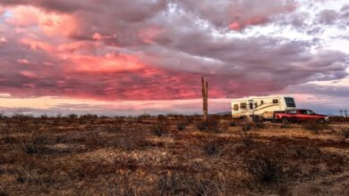 A landscape photo of an RV in the distance under a red sky sunset at a BLM boondocking site outside Phoenix, Arizona.