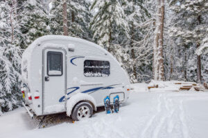 Oversize RV Transport: What Dealers Can Learn From Heavy Equipment Hauling 3 A travel trailer RV covered in snow, illustrating weather delays.