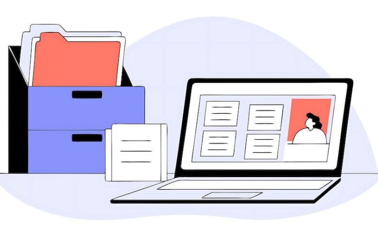 Files in a file box and a laptop open on a desk to demonstrate using dealership management systems (DMS).