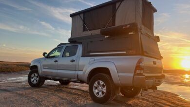 A PahaQue Custom Inc. tent on the top of a truck camper with a sunset background.