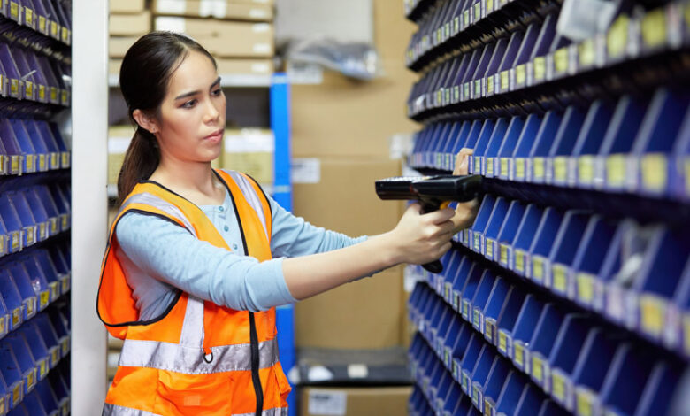 A woman using laser barcode scanner and looking at parts storage cabinet to demonstrate organizing an RV dealership parts and accessories department.