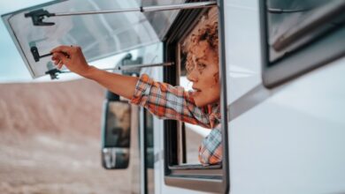 A woman opening her camper van home window at an off-grid destination, illustrating looking at what's ahead for the RV industry