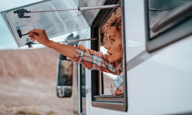 A woman opening her camper van home window at an off-grid destination, illustrating looking at what's ahead for the RV industry