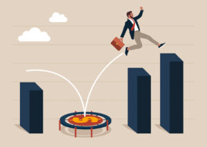 A business man jumping from a trampoline to another part of a bar graph to illustrate economic rebound.