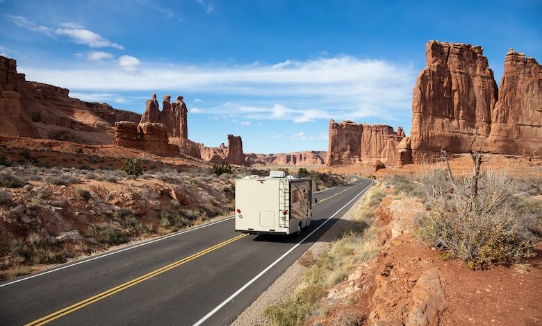 Camper riding on a Scenic road in the red rock canyons during a vibrant sunny day. Taken in Arches National Park, located near Moab, Utah, United States.