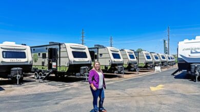 A woman in a purple blazer standing in front of Forest River RVs at Pikes Peak RV dealership in Colorado Springs, Colorado.