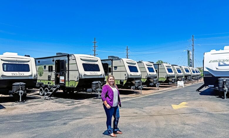 A woman in a purple blazer standing in front of Forest River RVs at Pikes Peak RV dealership in Colorado Springs, Colorado.
