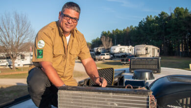 A male RV technician sitting on the roof of an RV to demonstrate how mobile RV techs can aid in reducing RECT in dealerships.