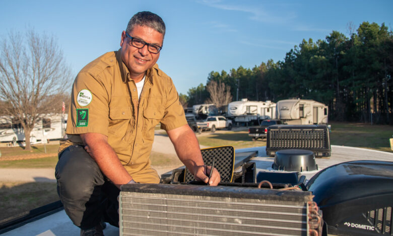 A male RV technician sitting on the roof of an RV to demonstrate how mobile RV techs can aid in reducing RECT in dealerships.