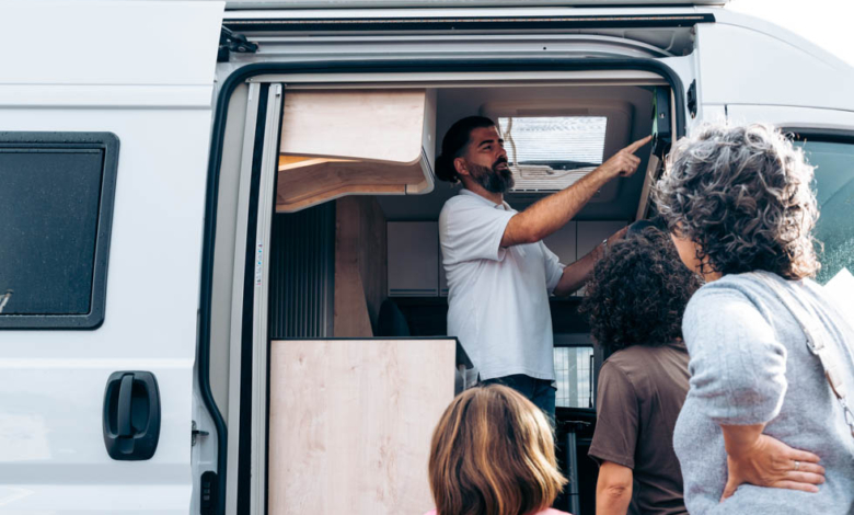 Salesman enthusiastically explaining features of a camper van to a family, who is engaged in the buying process and considering their options, illustrating success in peak season.