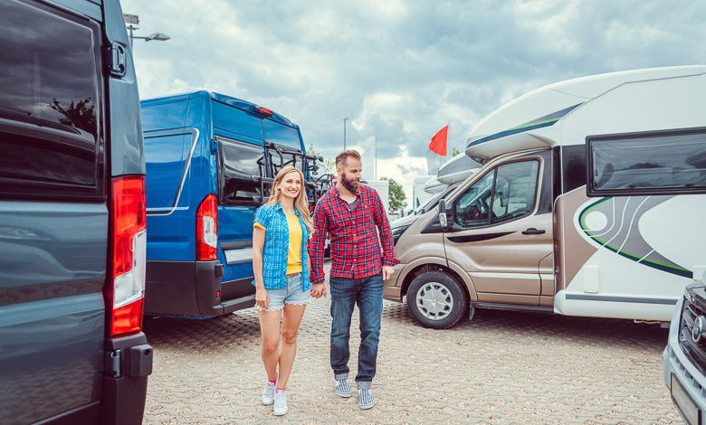 Couple facing abundance of choice in camper vans to buy standing between the vehicles, illustrating how to analyze buyer behavior.