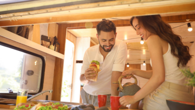 Happy young couple having breakfast in trailer view from outside. Camping vacationUntitled