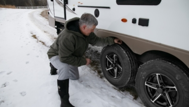 A man kneeling next to an RV, demonstrating the need to inspect RV tires for UV and ozone damage.